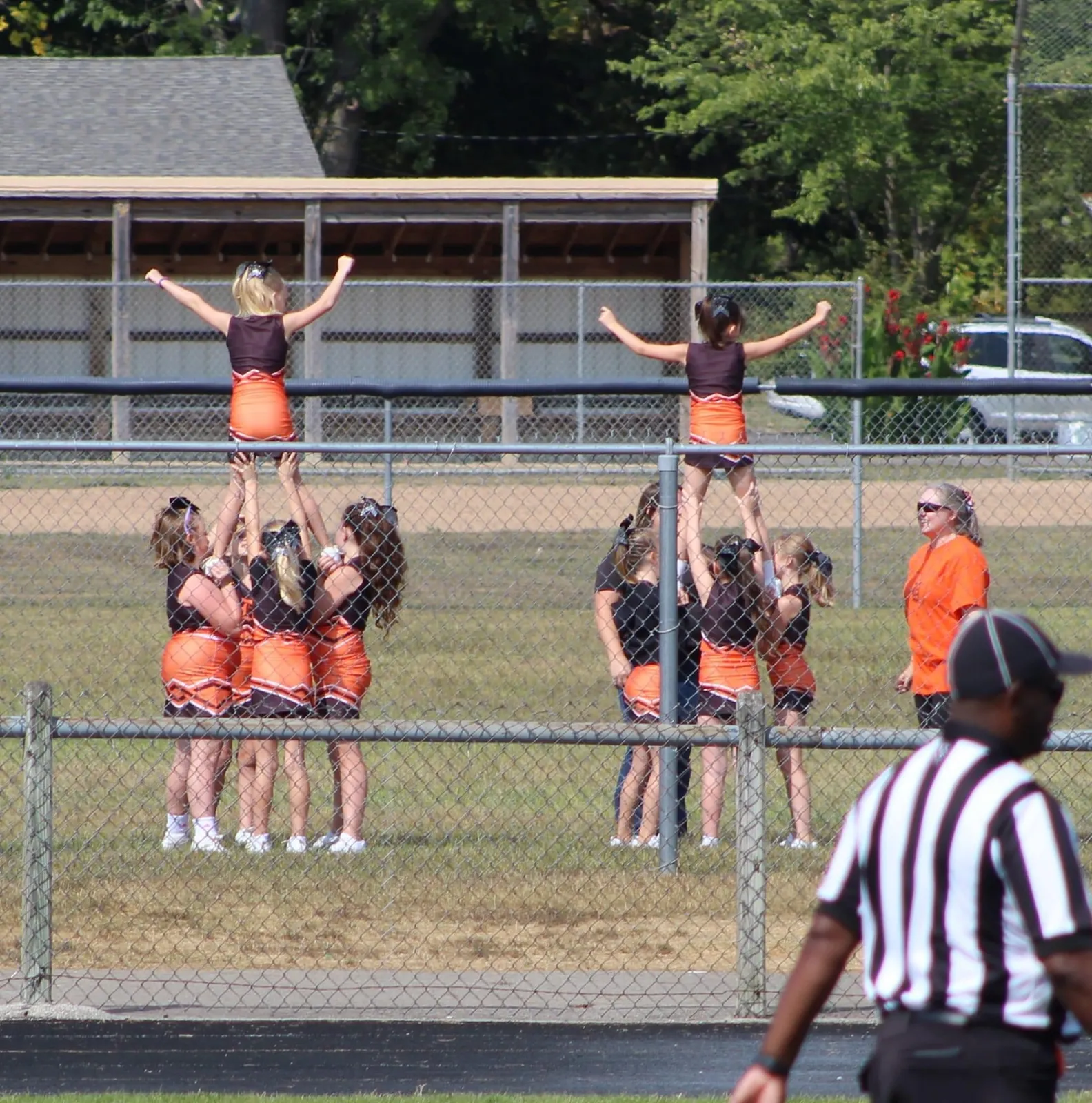Jr Pacers cheerleaders stunting along the fence